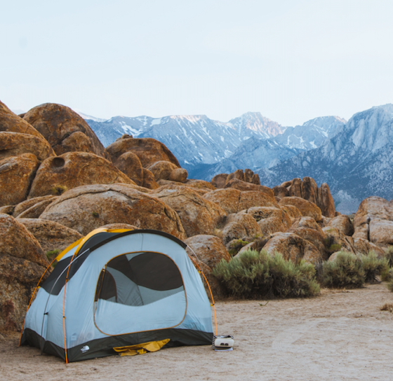 A tent in a campground surrounded by red rock.