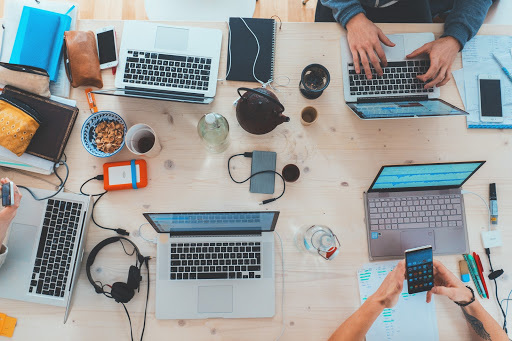 An aerial shot of a group of people working on laptops and phones. 