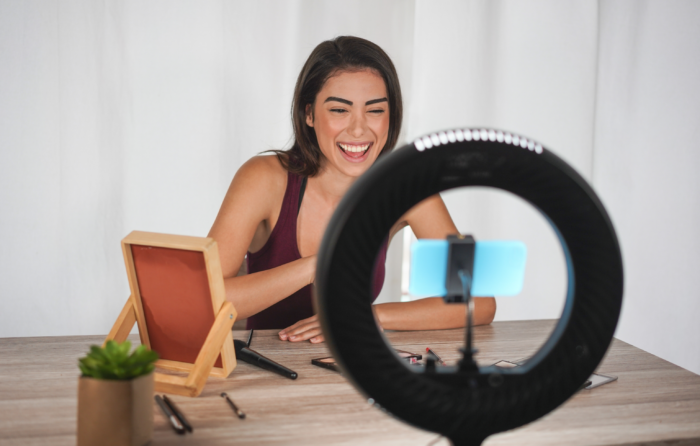 Makeup content creator using cellphone and ring light to shoot a video for social media marketing