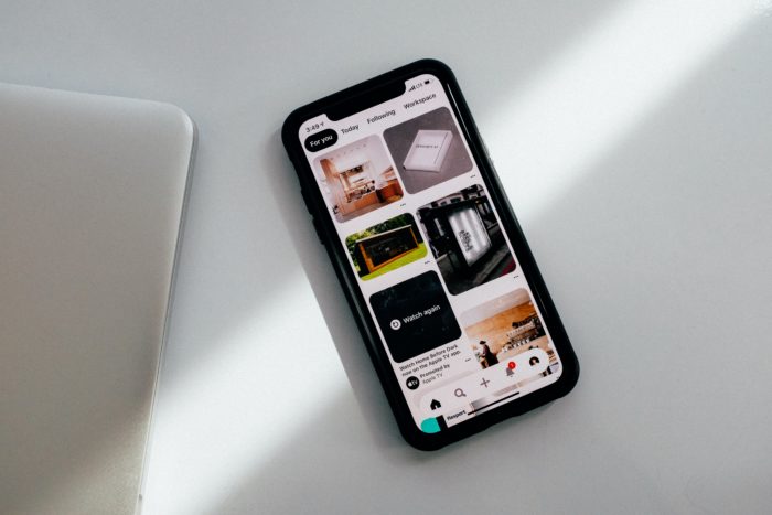 Cellphone laying on a table with Pinterest feed on screen.