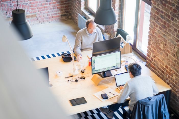 Two men sitting at desks working on their computers.