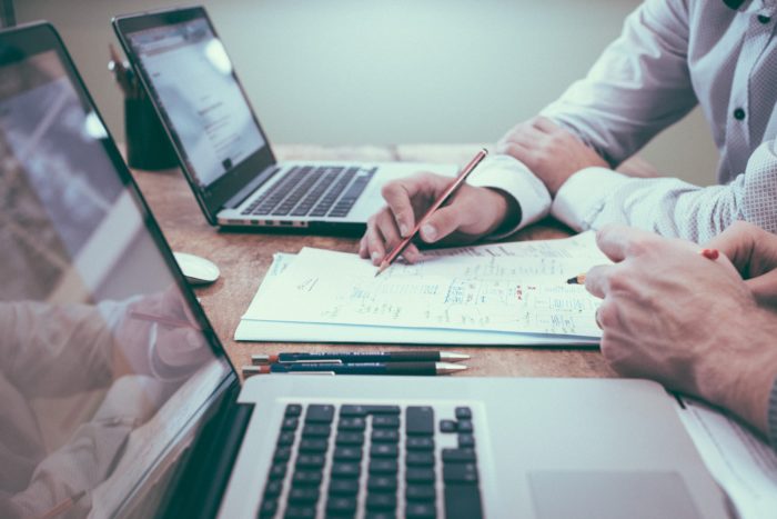 Two people reviewing analytics on papers and computers.