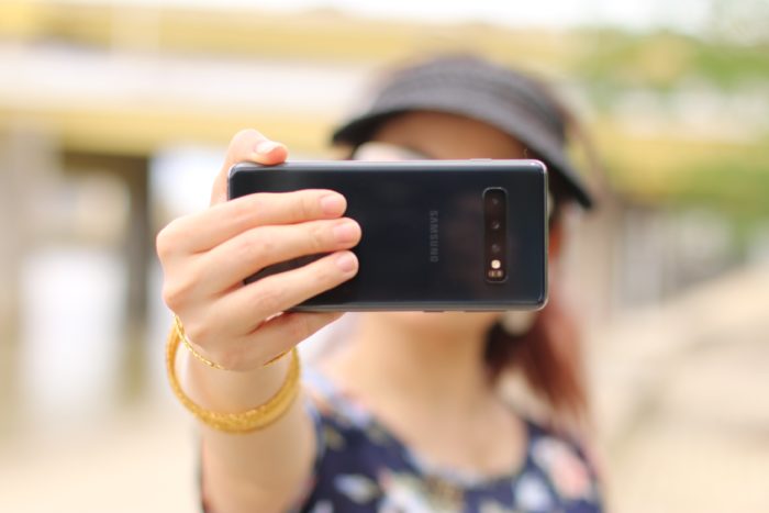 A young woman filming herself with a phone.