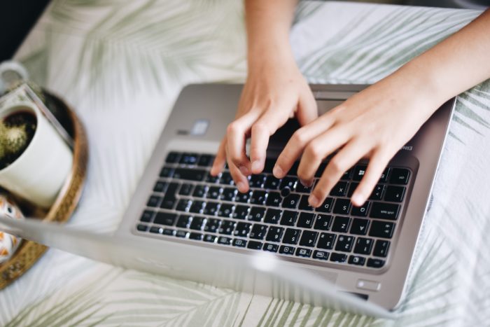 A view of a person's hands typing on a computer.