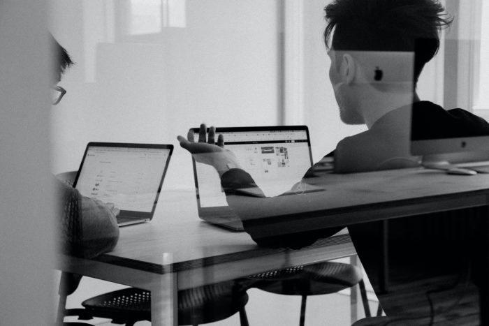 Students at desk with laptops having a discussion