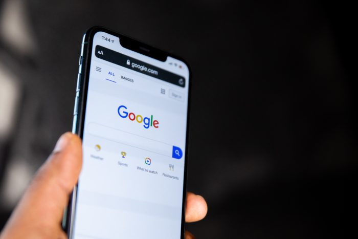 Hand holding cellphone showing Google search bar